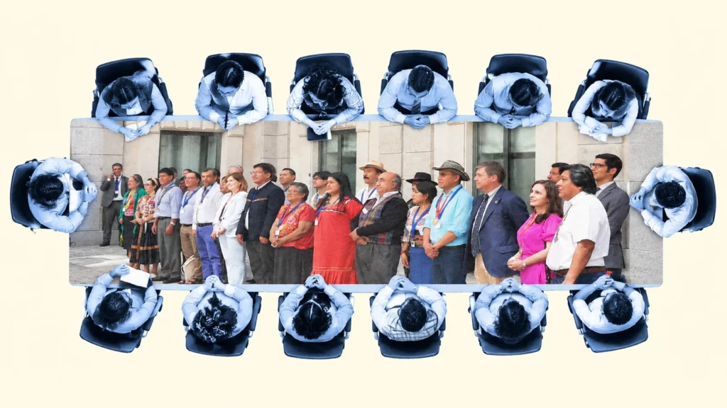 Vista cenital de una mesa de reuniones con la foto de grupo del 30 aniversario del FILAC impresa sobre el tablero y personas sentadas alrededor