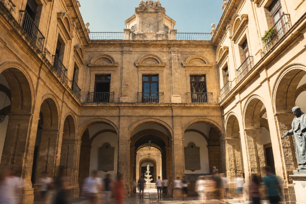 Patio con arcadas de un edificio histórico de Sevilla con paseantes en movimiento